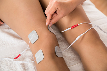 Therapist Placing Electrodes On Woman's Knee - obrazy, fototapety, plakaty