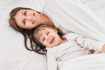 Mother playing with daughter on the bed