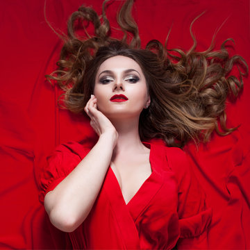 Woman in red dress posing with waving fabric, the girl touches