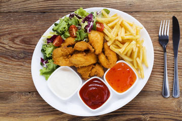Nuggets and chips on a plate served with dip and salads