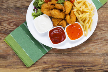 Nuggets and chips on a plate served with dip and salads