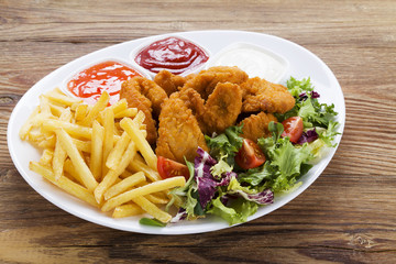 Nuggets and chips on a plate served with dip and salads