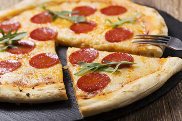 Pizza peperoni on stone black try with rocket and mozzarella che