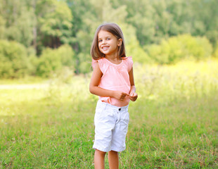 Portrait of happy little girl outdoors in sunny summer day