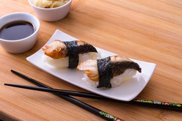 Two nigiri sushi eel with soy sauce on bamboo table