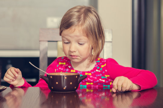 Beautiful little girl eating soup.
