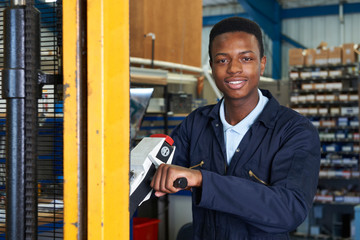 Factory Worker Using Powered Fork Lift To Load Goods