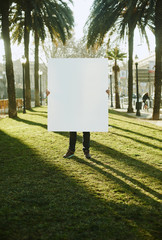 Man holding empty blank white poster or board at city backgound