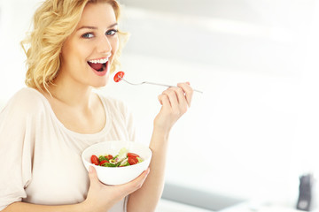 Young woman eating salad in the kitchen