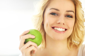 Young woman eating an apple at home