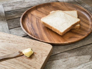 Toast bread on wooden plate and wooden breadboard with butter