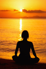 A silhouette of meditating woman at the sea shore 