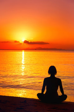 A silhouette of meditating woman at the sea shore 