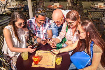 Group of friends in a bar having fun with smartphone 