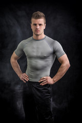 Naklejka premium Portrait of handsome young man in grey t-shirt on black 
