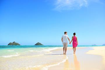 Beach couple holding hands walking on Hawaii
