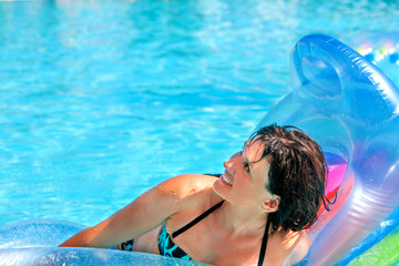 Woman swimming on inflatable beach mattress.