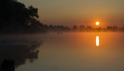 Naklejka na ściany i meble Fisherman on the sunrise, sunrise on the lake