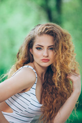 Naklejka premium Beautiful young woman with gorgeous curly fair outdoors