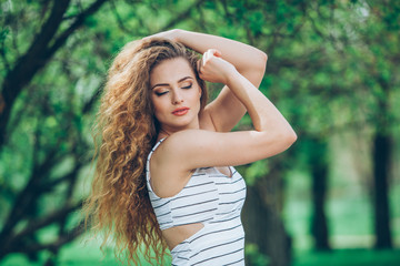 Naklejka premium Beautiful young woman with gorgeous curly fair outdoors