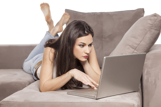 Concerned Girl Lying On The Couch And Working On Her Laptop