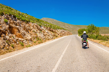 Young man driving scooter on empty asphalt road, Greek Island Ka