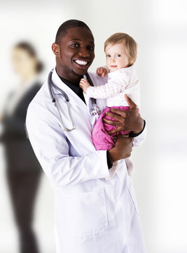 Male doctor holding baby girl.