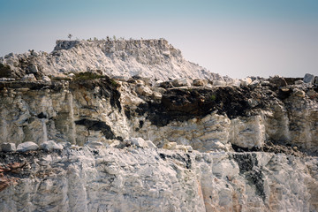 Fototapeta na wymiar Steep Rocky Cliffs in an Open Pit Marble Mine