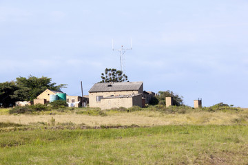 Fototapeta premium Open Grassland with Rural Farm Buildings in Background