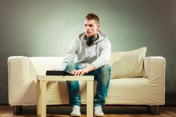 man with headphones sitting on couch with tablet