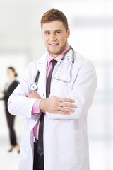 Young happy male doctor with folded arms.