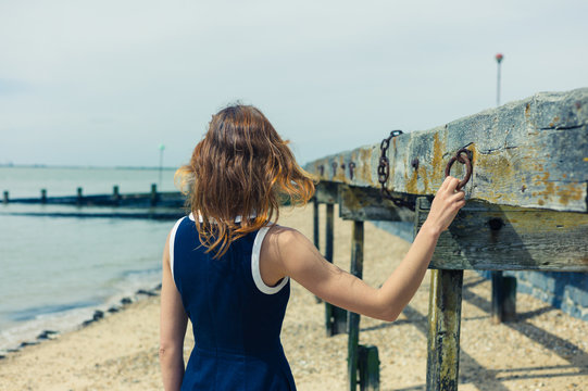 Young woman standing on beach with old wooden structure