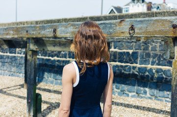 Young woman standing on beach with old wooden structure