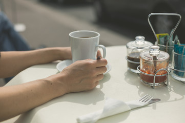 Woman drinking coffee at table outside