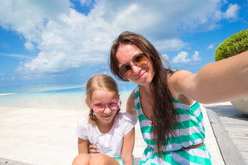 Fototapeta na wymiar Mother and little girl taking selfie at tropical beach