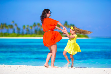 Little adorable girl and happy mom enjoy beach vacation