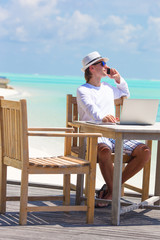 Business man calling by cell phone on white beach