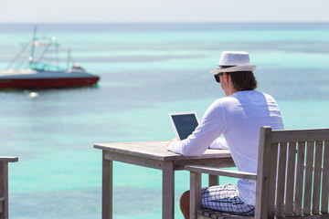 Young man with tablet computer during tropical beach vacation