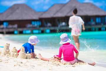 Two little girls and happy mother playing with beach toys on