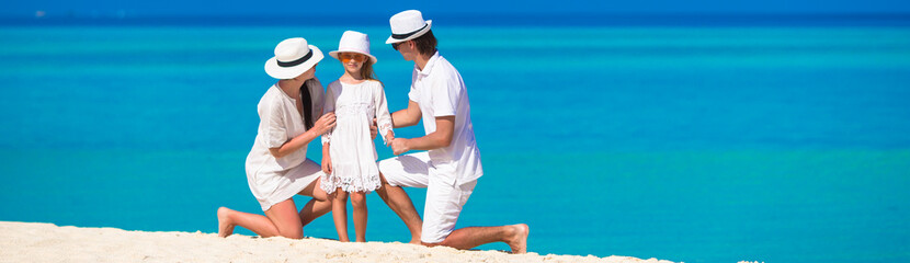 Young family of three on white beach during summer vacation