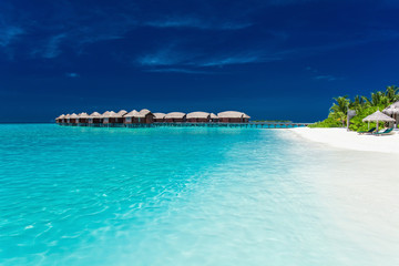 Fototapeta na wymiar Overwater bungallows in blue lagoon on tropical island