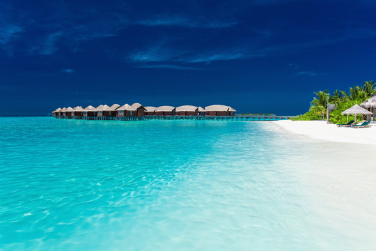 Overwater bungallows in blue lagoon on tropical island