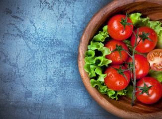 wooden bowl with cherry tomatoes on blue table