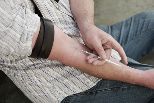 Man injecting himself with a small hypodermic