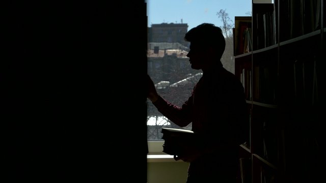 Silhouette guy puts the book in its place in the library. it