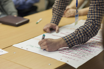 Male Host Writing on a Big Paper Sheet in Front of Group of Peop