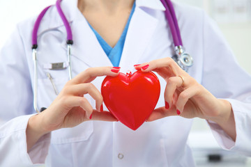 Young woman doctor holding a red heart, isolated on white