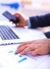 Businessman sitting at table with laptop and documents