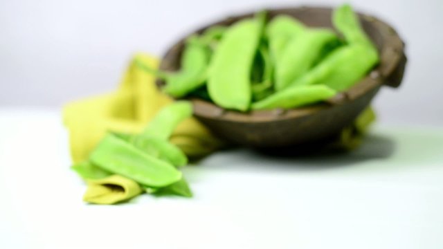 Broad beans of peas on light green wood table background.