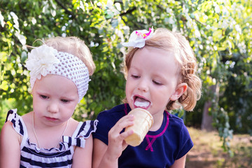 Pretty little girls (sisters) eating ice cream in the summer the